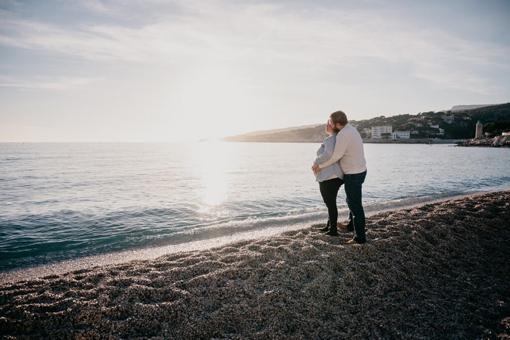 Séance couple grossesse, sur une plage à Cassis, le couple regarde à l'horizon