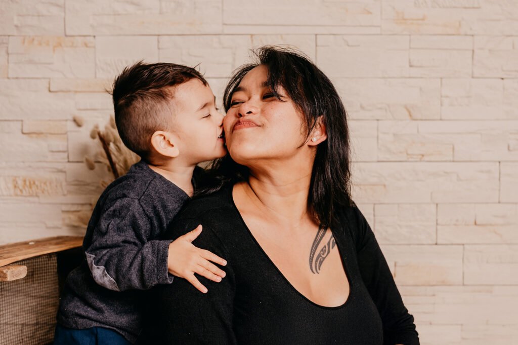 Photographie de la maman et son petit garçon qui vient lui faire un bisous sur la joue, photographe aix en provence